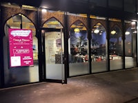 the entrance to a restaurant at night with a sign